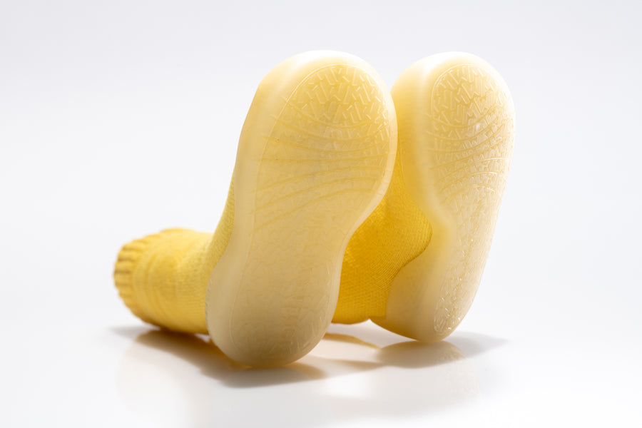 The grippy soles of a pair of yellow sock shoes