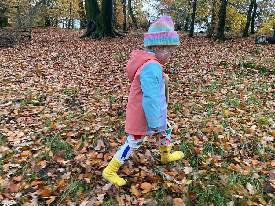Toddler walking through fall leaves in yellow Meriweather sock shoes